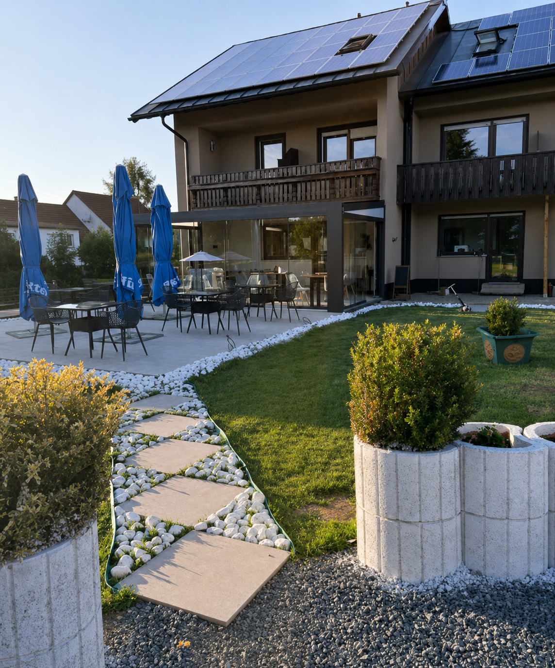Die Villa Johannes vom Garten aus mit Terrasse, Sonnenschirmen und Wintergarten